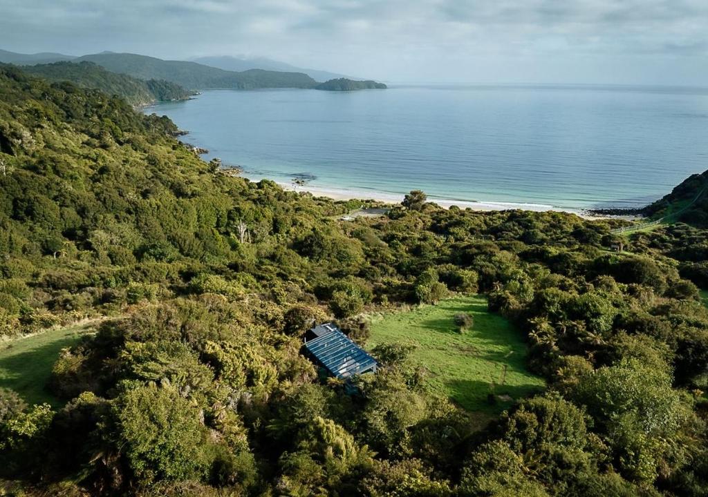 Stewart IslandにあるTokoeka PurePodの海辺の緑豊かな丘陵地帯の空中風景