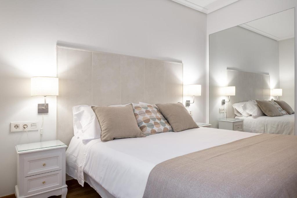 a white bedroom with two beds and two lamps at Dolce Vita Centro in Vitoria-Gasteiz