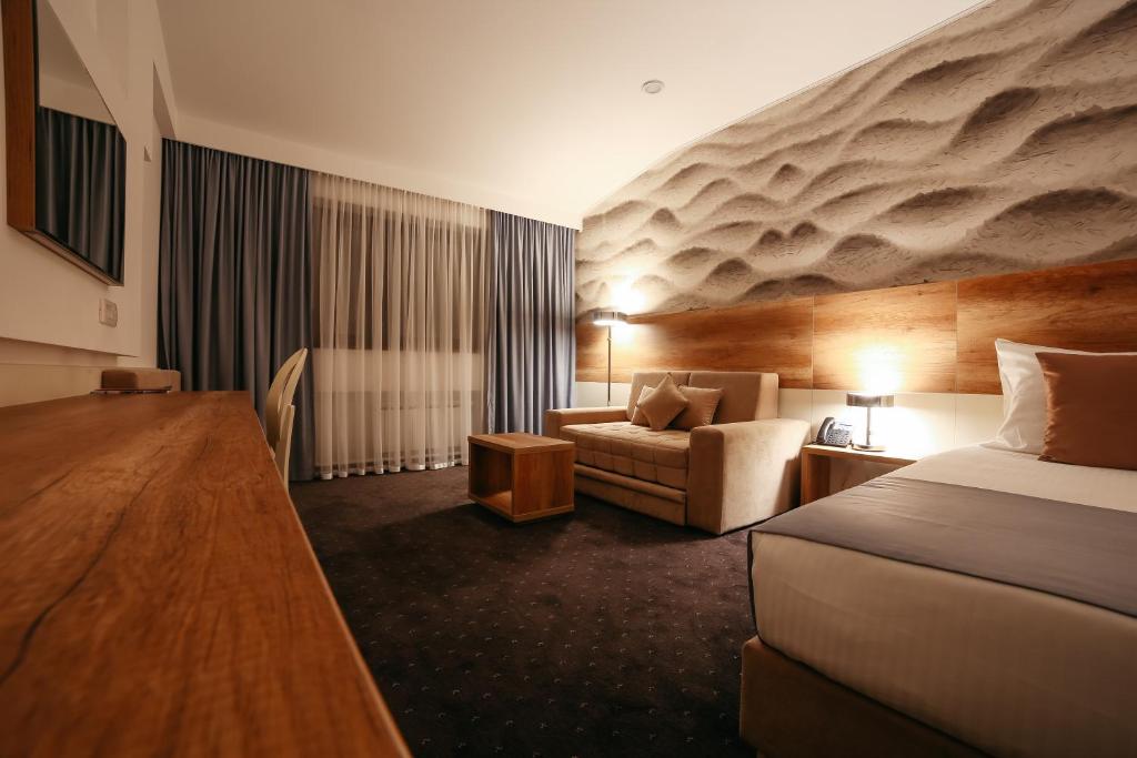 um quarto de hotel com uma cama e um sofá em Hotel Santiny em Sveta Nedjelja