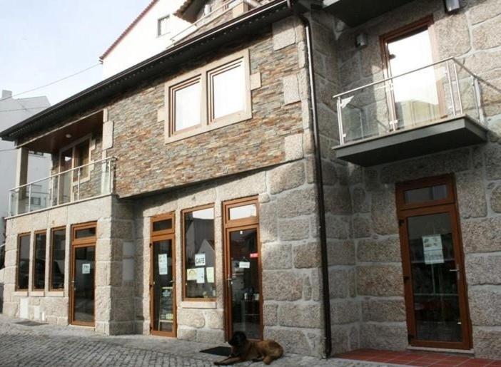 a dog laying on the ground in front of a building at Recantos da Estrela in Sabugueiro