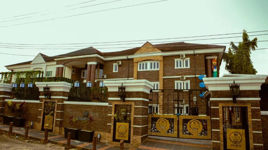 uma grande casa de tijolos com uma cerca em frente em TN MAX LUXURY HOME em Enugu