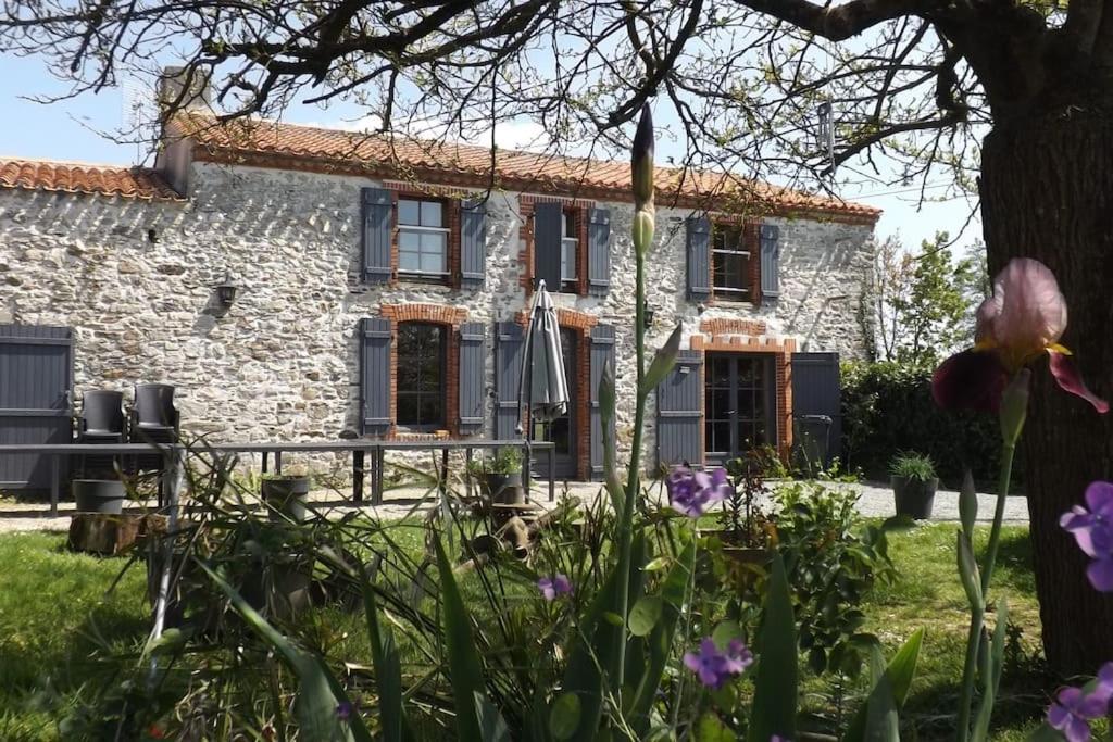 a stone house with flowers in front of it at Gite les Farfadets - 12 personnes maxi in Grand-Landes