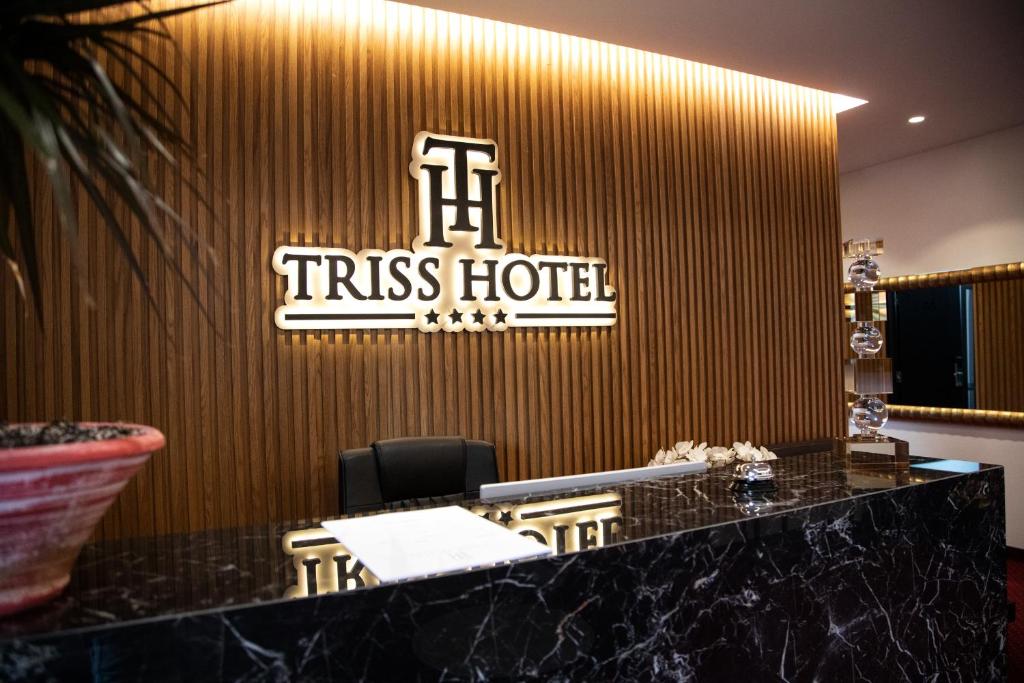 地拉那的住宿－Triss Hotel，墙上挂着酒店标志的酒店前台