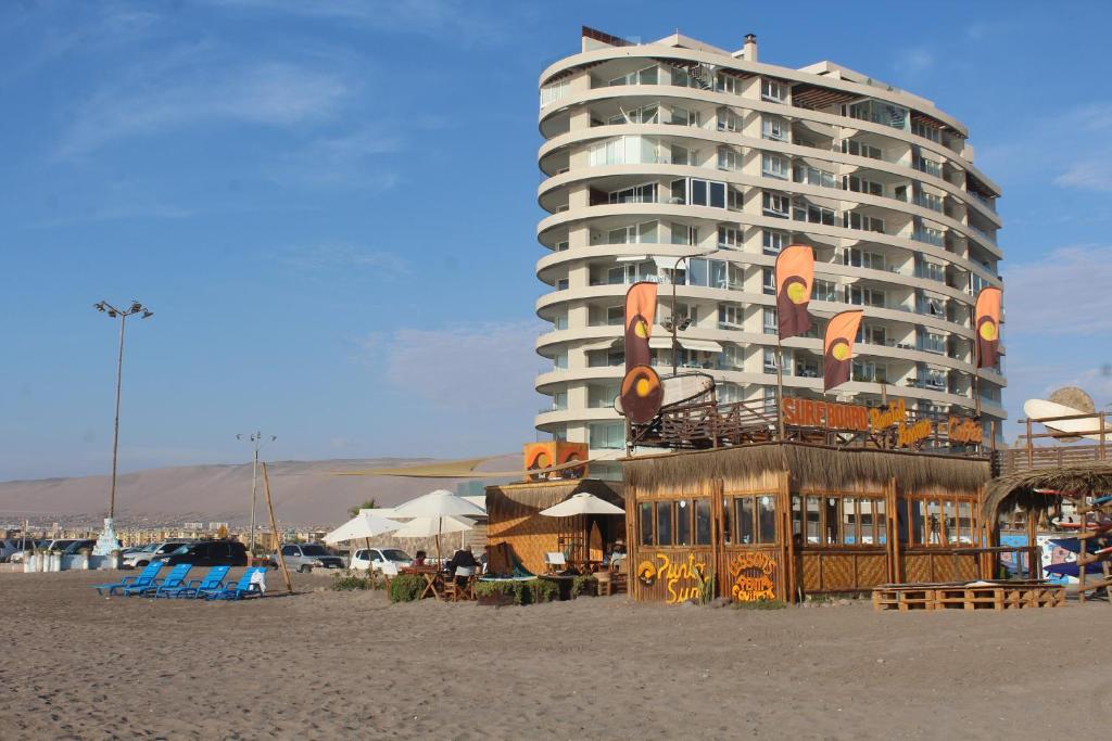 a hotel on the beach with a building in the background at Departamento Full 3D 2B Cerca de Playas en Arica in Arica