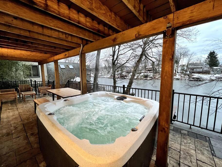 a jacuzzi tub on a porch with a view of the snow at Cozy Cabin on the Lake w/ HotTub in Hopatcong