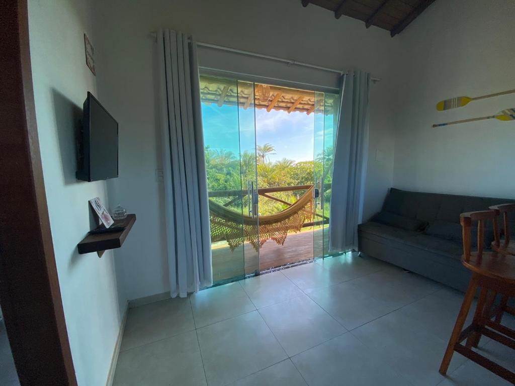a living room with a couch and a large window at Villa Ohana - Flats in Taipu