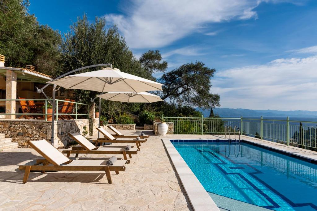 a pool with lounge chairs and an umbrella next to a swimming pool at Loggos View House in Mastorátika