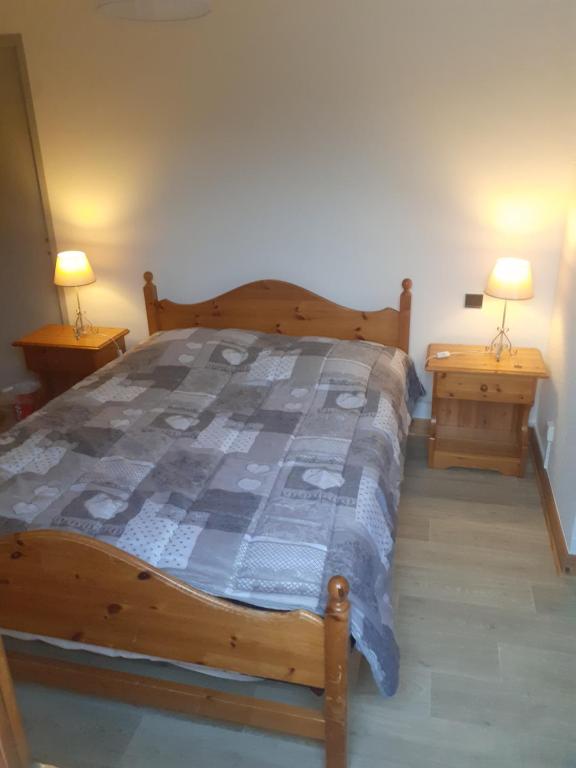 1 dormitorio con 1 cama de madera y 2 mesitas de noche en Chambre avec SdB, WC et entrée indépendantes pour les locataires, en Aime La Plagne