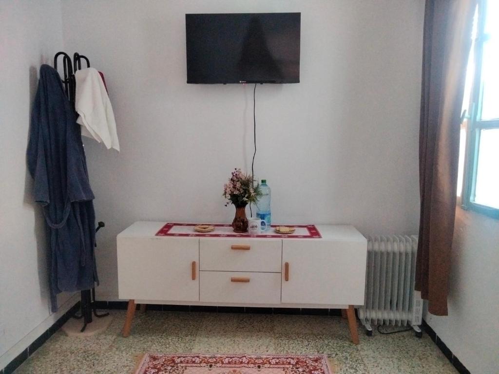 a white cabinet with a vase of flowers on it at Dar Hkaïem in Sousse