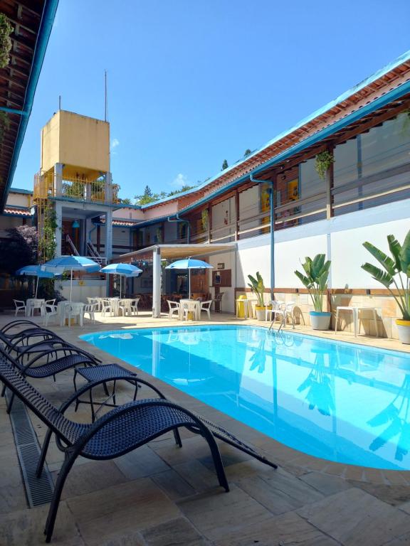 uma piscina com cadeiras e guarda-sóis ao lado de um edifício em Hotel e Pousada Pouso54 em Ubatuba