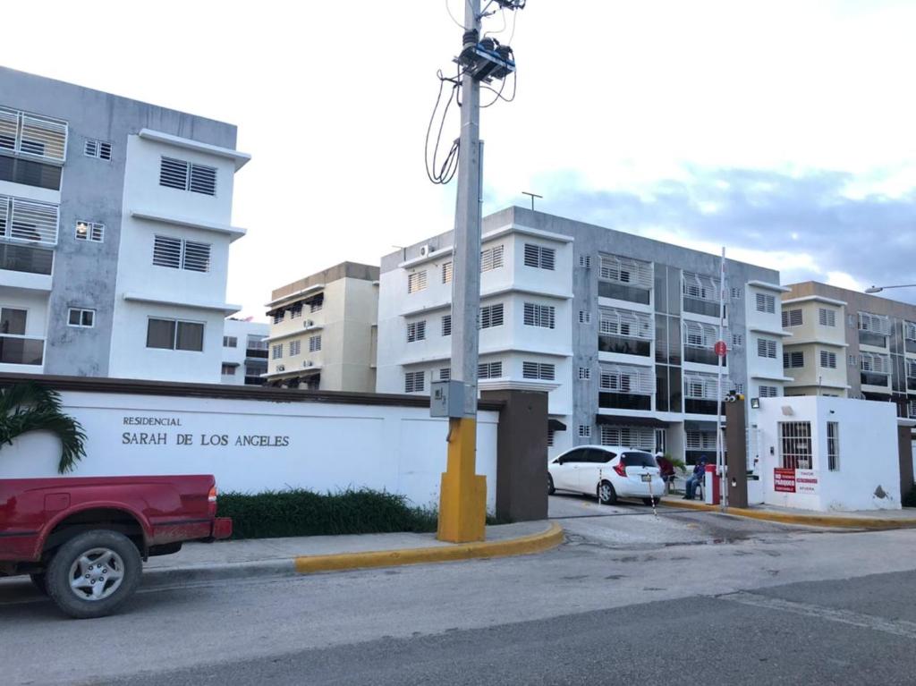 un camión rojo estacionado en un estacionamiento con edificios en Residencial sarah de los Angeles en San Juan de la Maguana