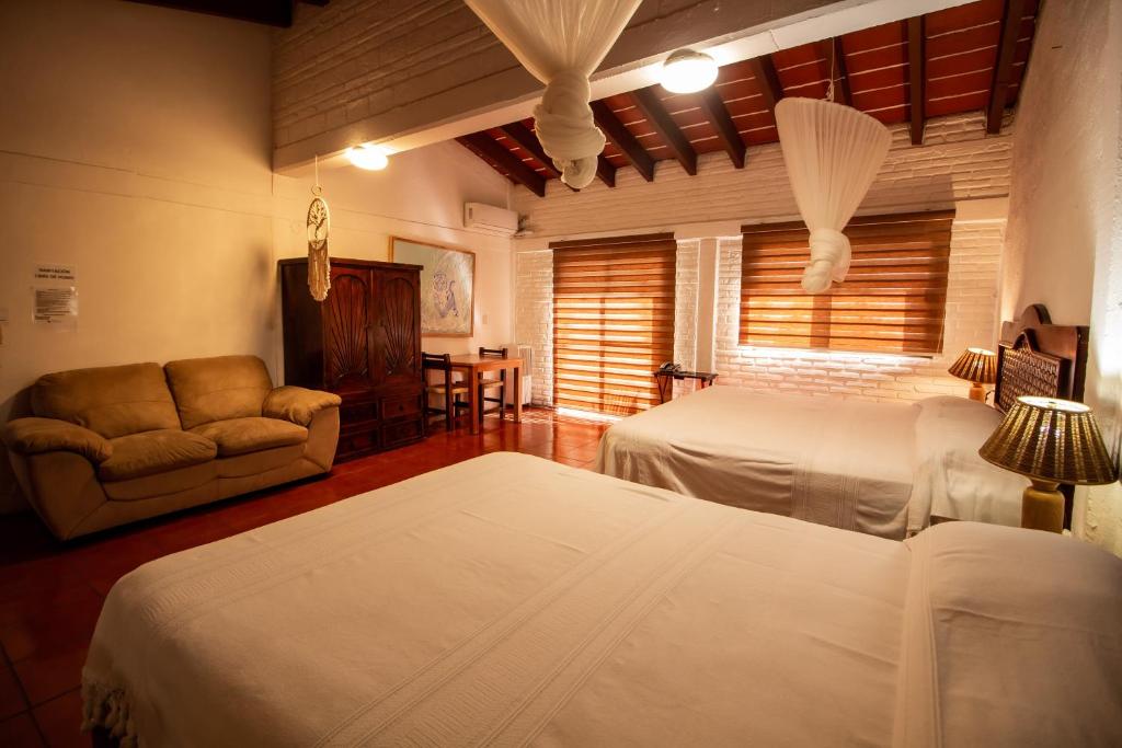 a bedroom with two beds and a couch and a window at Hotel boutique Teocalli in Tepoztlán