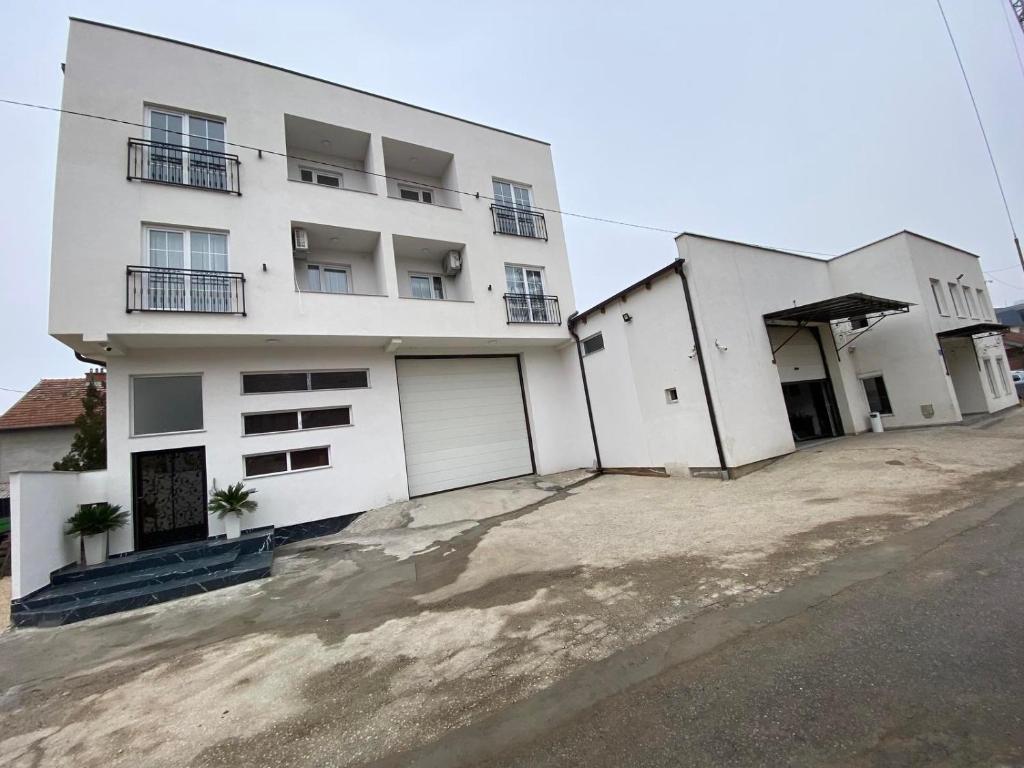 a white building with two garage doors in front of it at White Apartments in Kosovo Polje