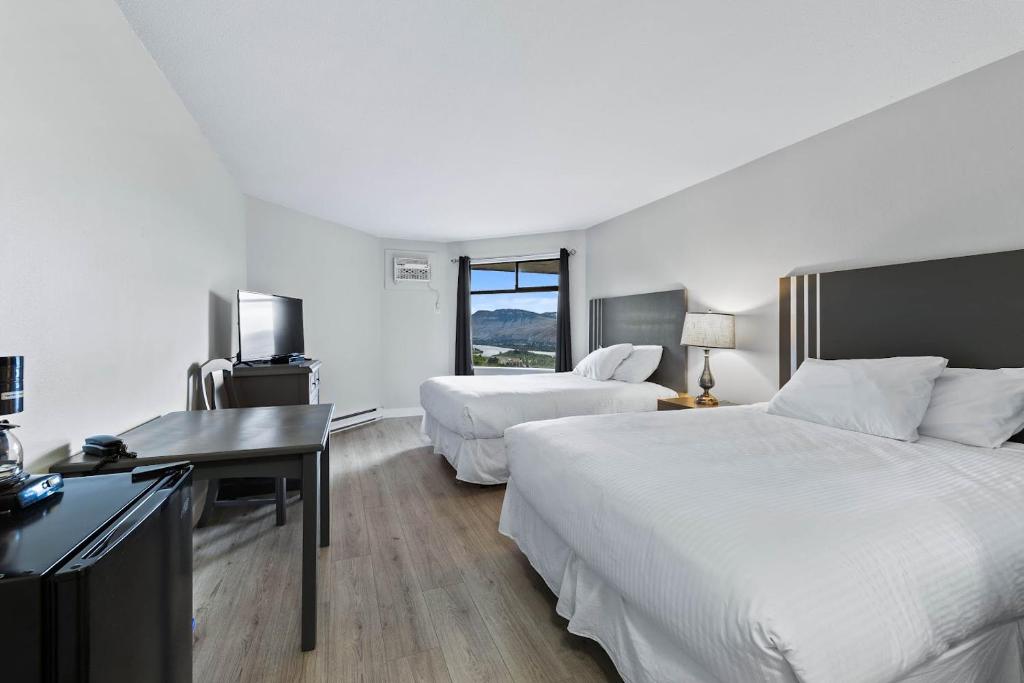 a hotel room with two beds and a desk at The Vista Inn in Kamloops