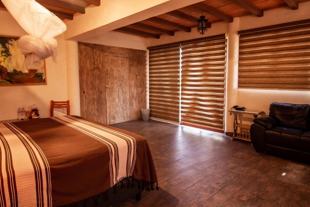 a bedroom with a bed and a chair and a window at Hotel boutique Teocalli in Tepoztlán