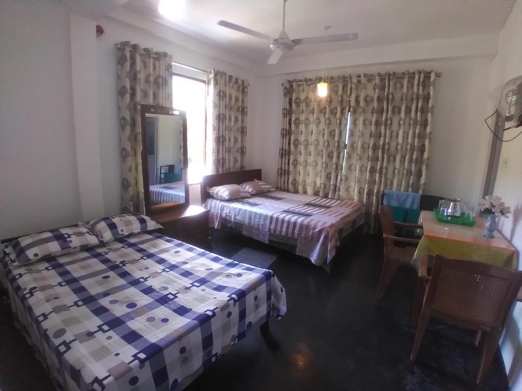 a bedroom with two beds and a table and a window at Jayathmaguest in Peradeniya
