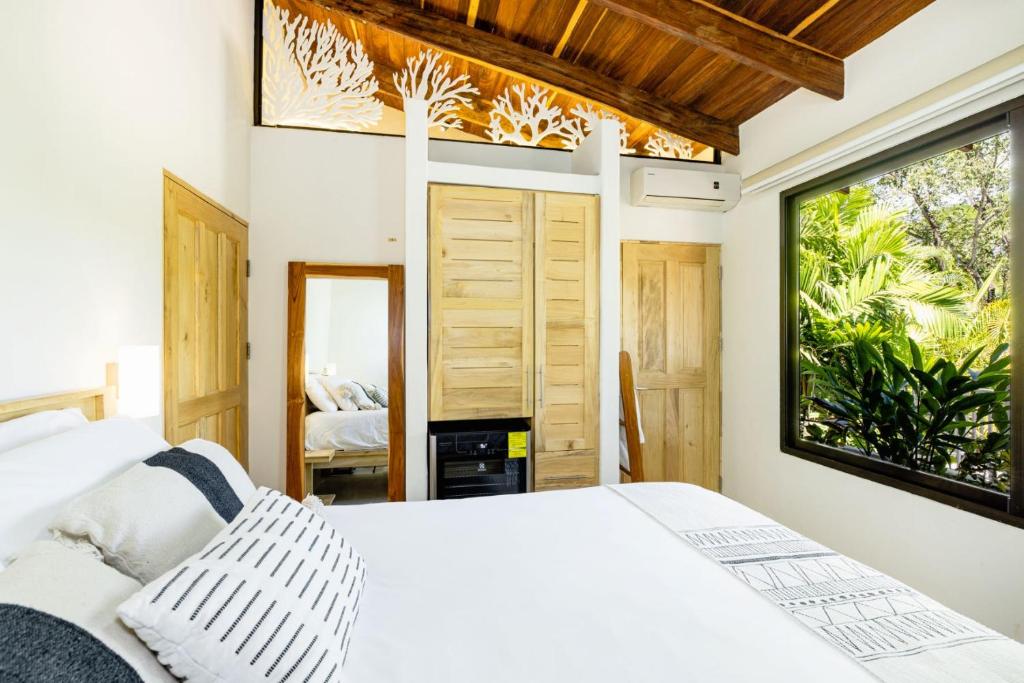 1 dormitorio con cama blanca y ventana en Cafe Playa Negra Hotel, en Playa Negra