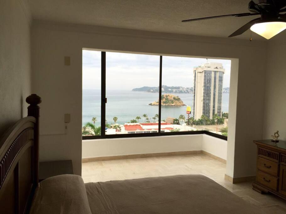 a bedroom with a large window with a view of the ocean at Departamento Familiar en Acapulco con Hermosa Vista! in Acapulco