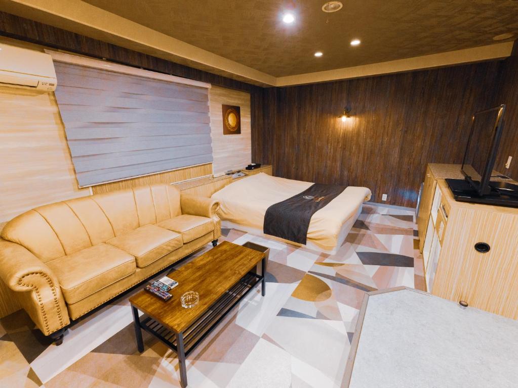 ein Zimmer mit einer Couch, einem Bett und einem Tisch in der Unterkunft GLAMROSE -Adult Only Motel- in Gotemba
