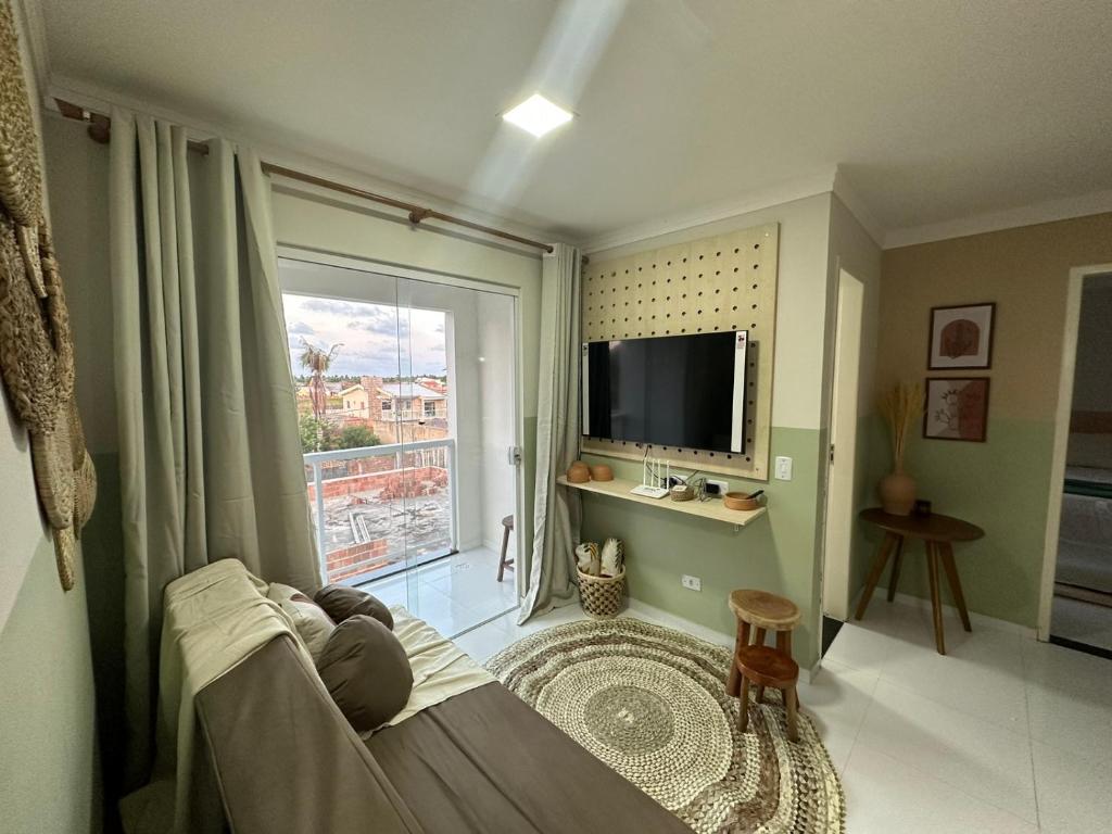 sala de estar con ventana grande y TV en Charmoso Apartamento em Maragogi, en Maragogi