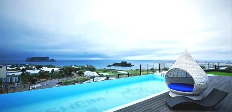 a swimming pool with a view of the ocean at Gladsheim Hotel in Seogwipo