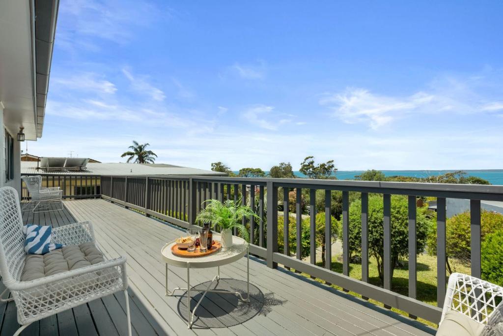 a balcony with chairs and a table and the ocean at A Pets Paradise by Experience Jervis Bay in Vincentia