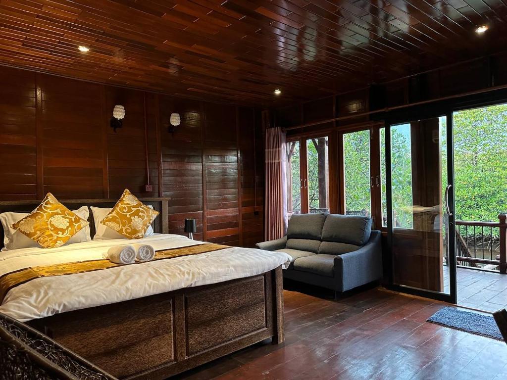 a bedroom with a bed and a couch and a chair at Prek Kdat Resort in Kampot