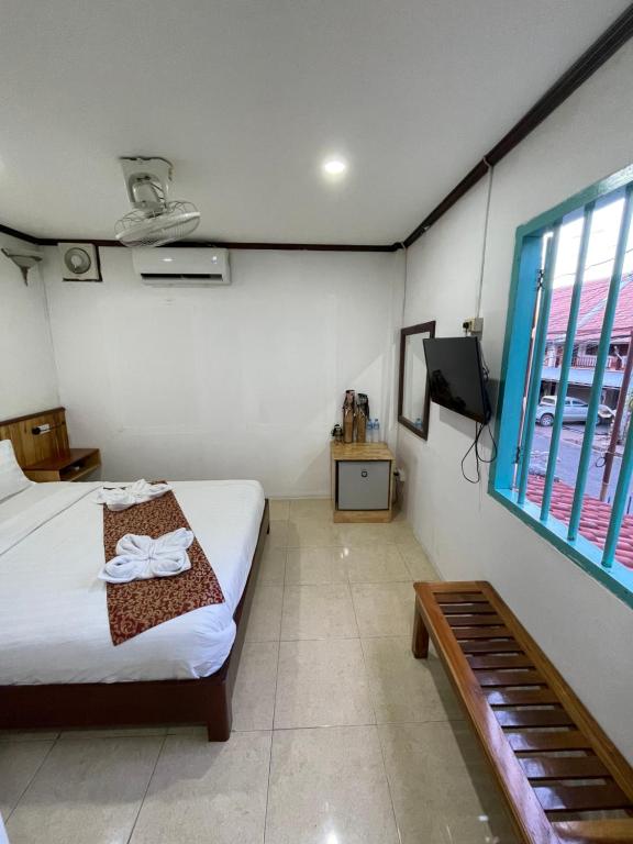琅勃拉邦的住宿－Little Friendly Guest House and Swimming Pool，一间卧室配有一张床,并在一间客房内配有电视。