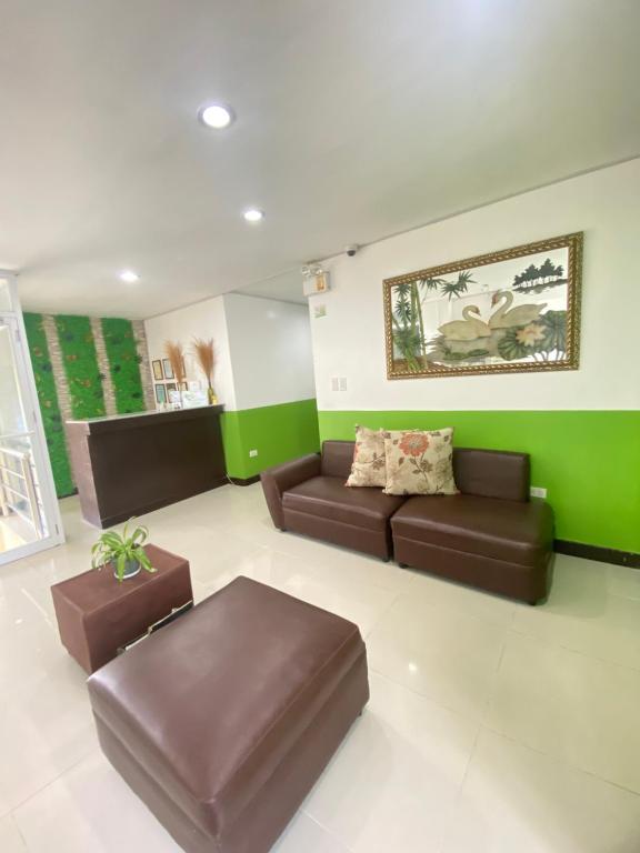 una sala de estar con muebles marrones y paredes verdes. en BOPEMPC Safari Hostel, en Tagbilaran City