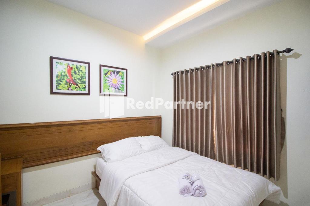 a bedroom with a bed and a curtain at Balmoral House Mitra RedDoorz near Ambarukmo Plaza Mall Yogyakarta in Yogyakarta