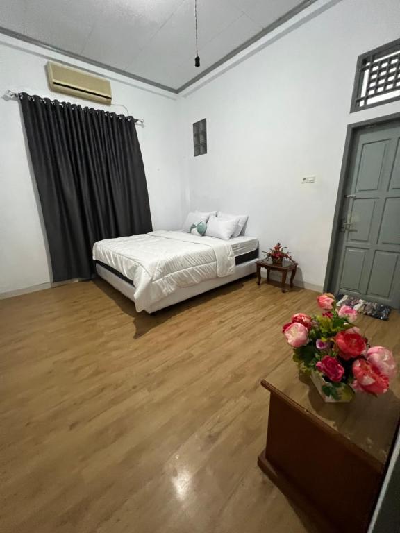 a bedroom with a bed and a table with flowers at Lorent Hostel Near Padang Beach in Padang