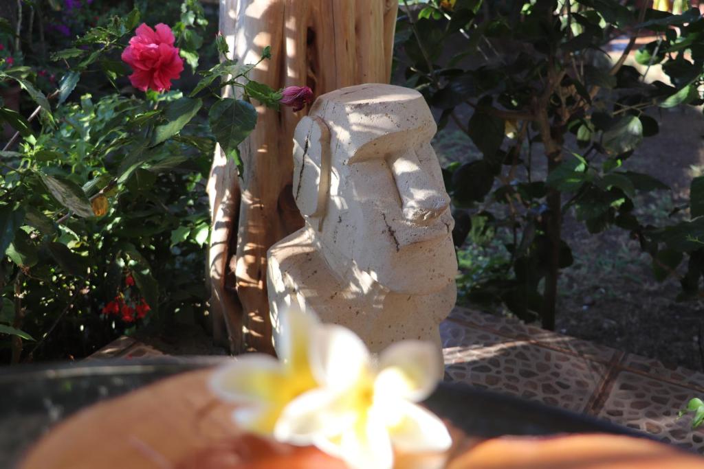a statue in a garden with a flower at Hostal Avareipua in Hanga Roa