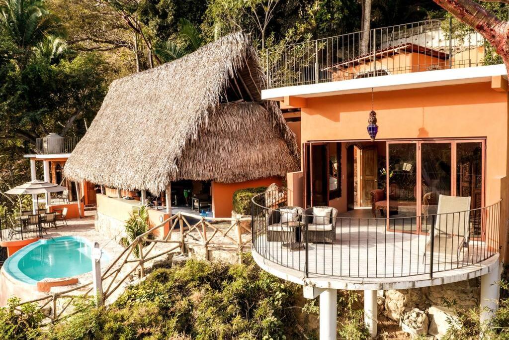 a house with a thatched roof and a swimming pool at Casa Flourish, Yelapa in Yelapa