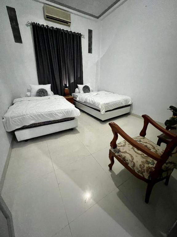 a room with two beds and a chair in it at Lorent Hostel Near Padang Beach in Padang