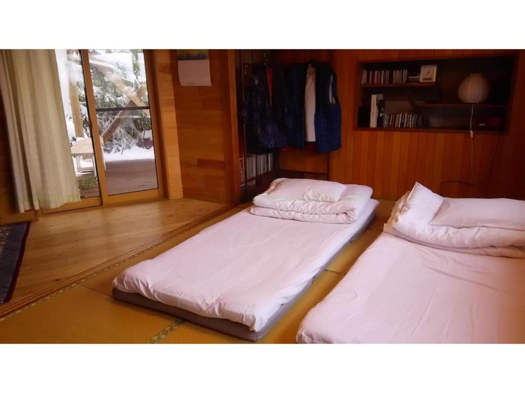 two twin beds in a room with a window at Tomareru sento taka no yu - Vacation STAY 00567v in Takayama