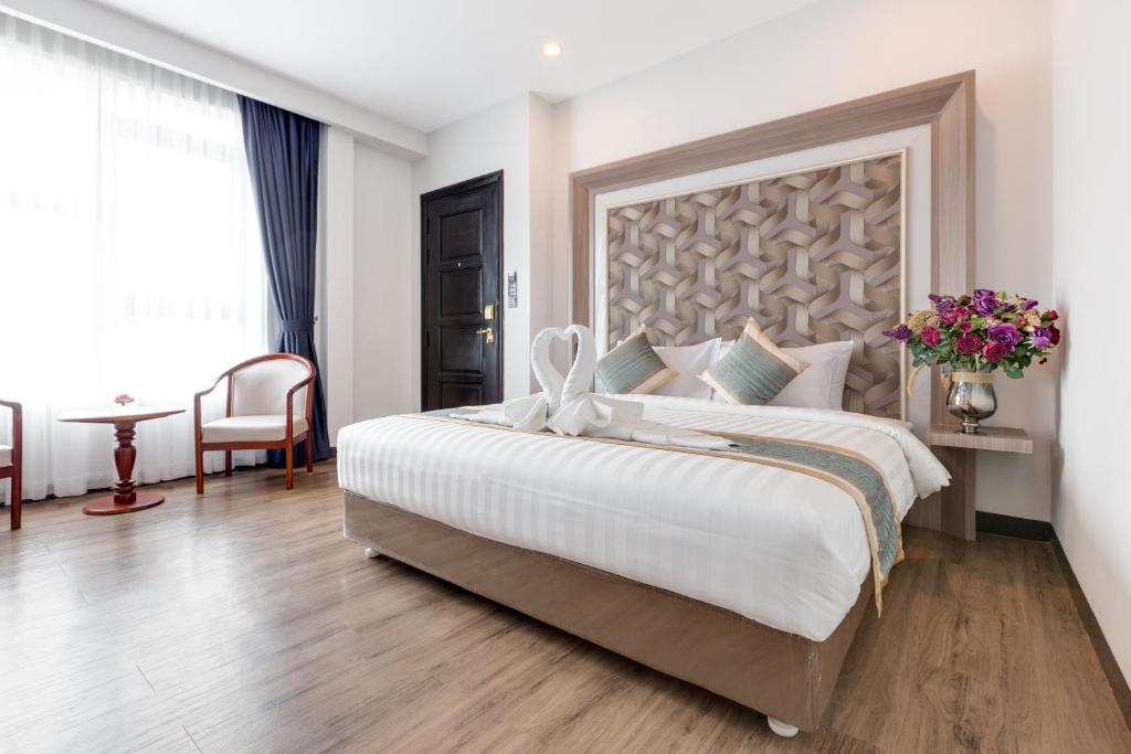 a bedroom with a large bed with a large headboard at New York Hotel in Phnom Penh