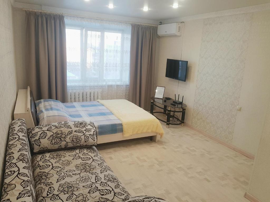 ein Hotelzimmer mit einem Bett und einem Sofa in der Unterkunft квартира in Pawlodar