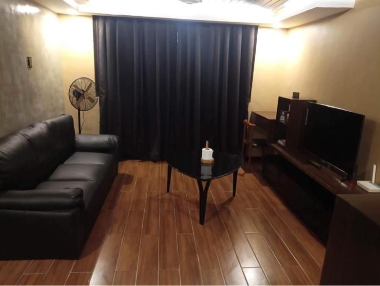 a living room with a couch and a table with a television at IV’s Condo w/ Netflix and Wi-Fi in Cainta