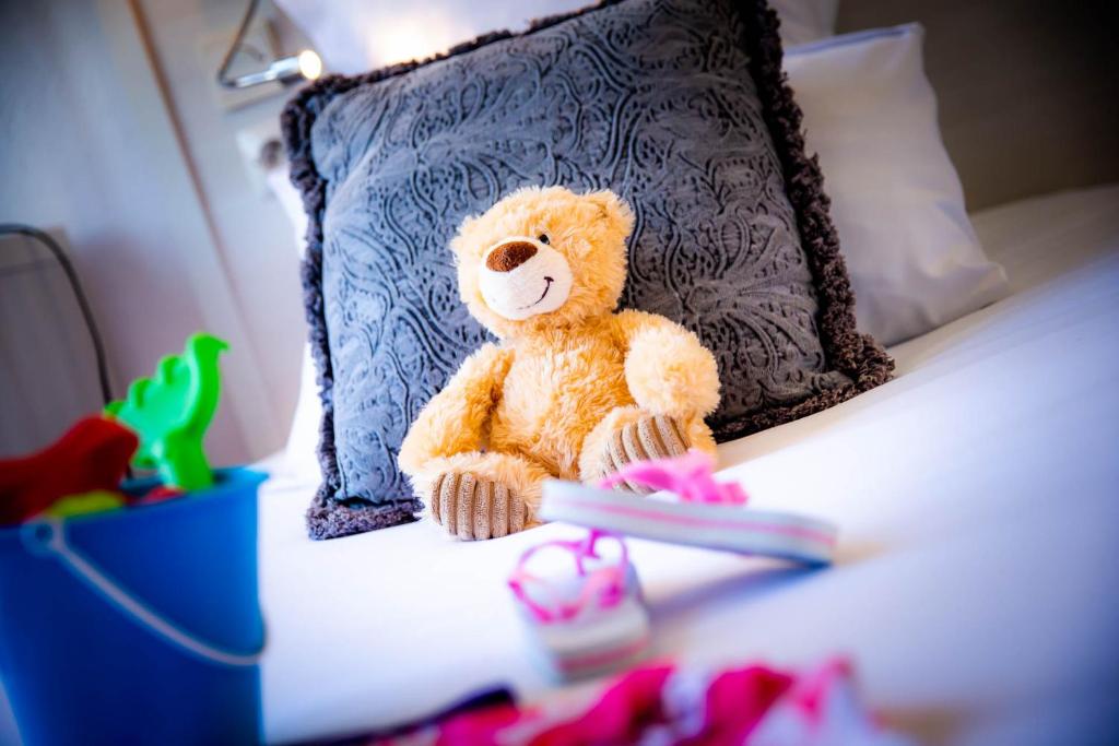 a teddy bear sitting on a bed next to a pillow at La Villa Andry in Ouistreham