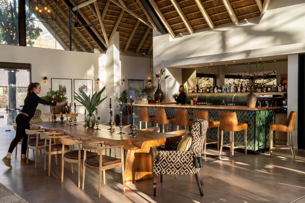 a woman standing at a table in a restaurant at Monwana in Thornybush Game Reserve