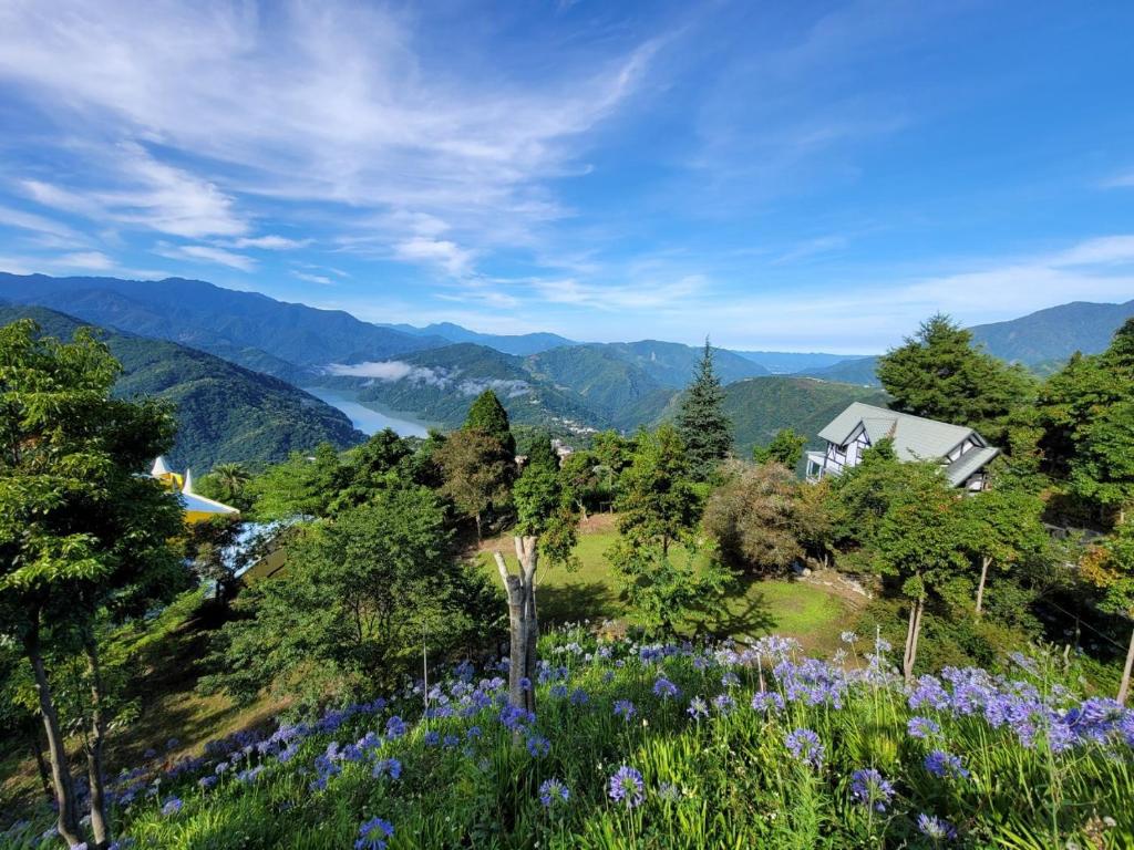 ein Haus auf einem Hügel mit Blumen und Bergen in der Unterkunft Zu Sin Garden B&B in Renai