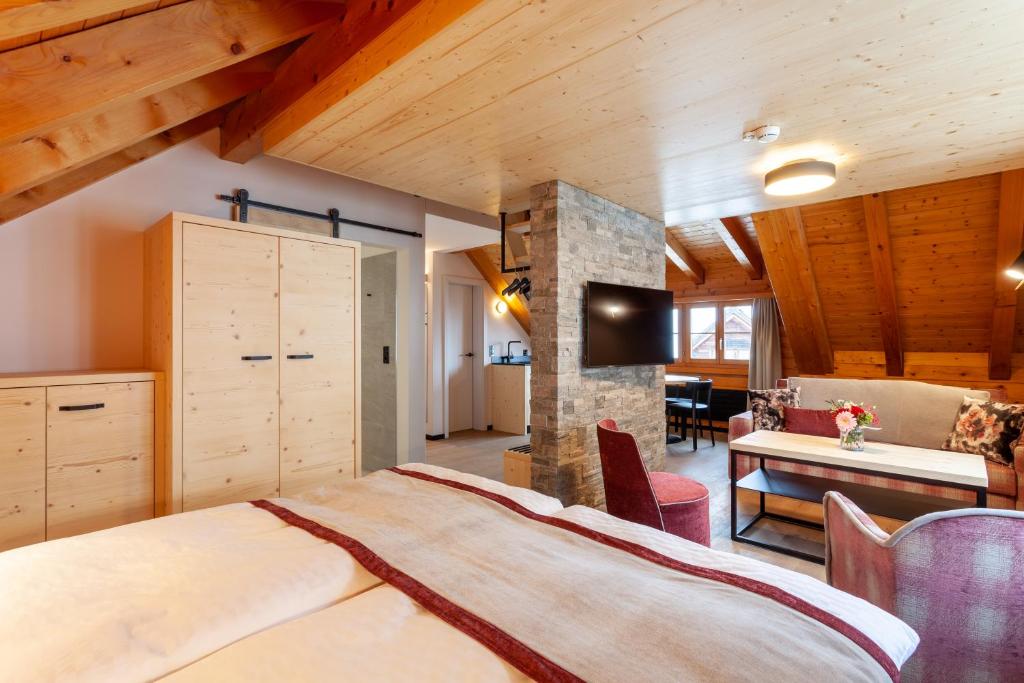 - une chambre avec un grand lit dans une pièce dotée de plafonds en bois dans l'établissement Sonne Andermatt Swiss Quality Hotel, à Andermatt