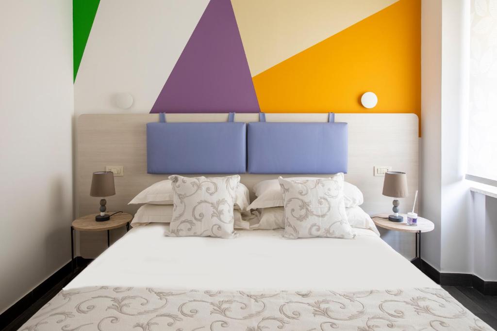 ein Schlafzimmer mit einem weißen Bett mit einer farbenfrohen Wand in der Unterkunft La Riviere Guesthouse Trastevere in Rom