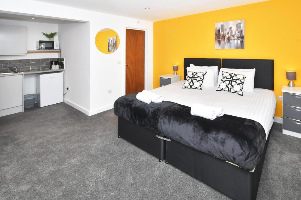 a bedroom with a large bed and a kitchen at NelsonStays Self-Contained Studios Stoke on Trent in Stoke on Trent
