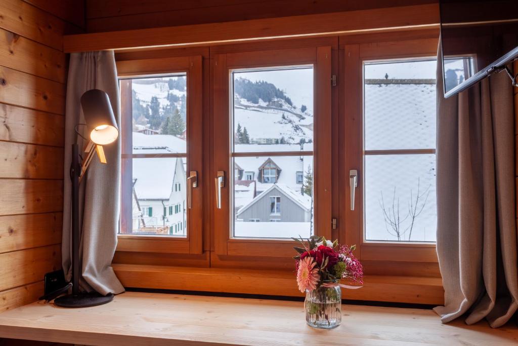 a vase of flowers sitting on a table next to a window at Sonne Andermatt Swiss Quality Hotel in Andermatt