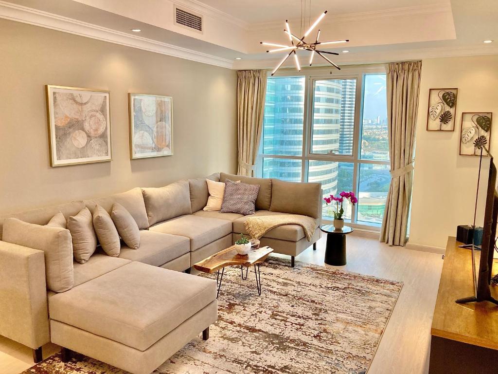 - un salon avec un canapé et une grande fenêtre dans l'établissement White Sage - Lakefront Apartment Amidst Parks With Lake Access, à Dubaï