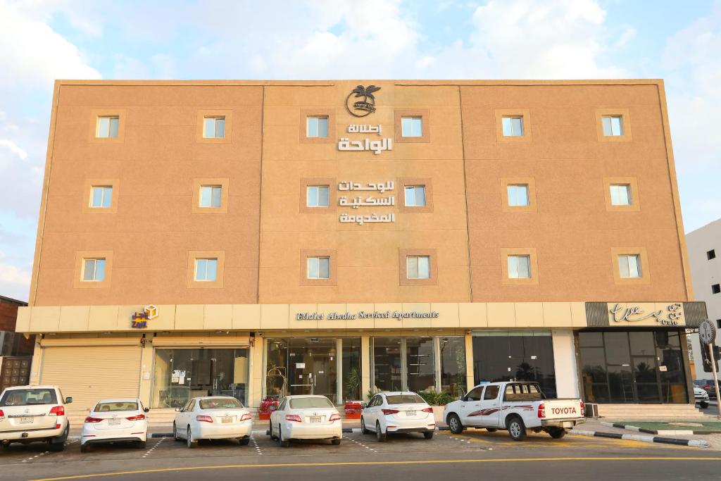 a large building with cars parked in a parking lot at إطلالة الواحة للشقق المخدومة in Al Majmaah