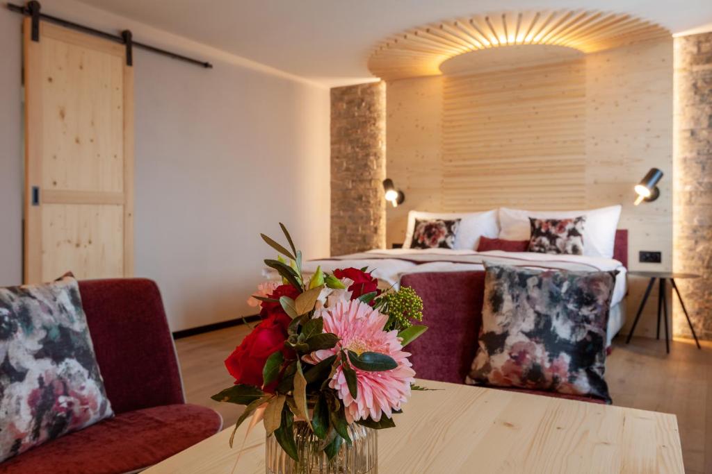 a bedroom with a bed and a table with a vase of flowers at Sonne Andermatt Swiss Quality Hotel in Andermatt