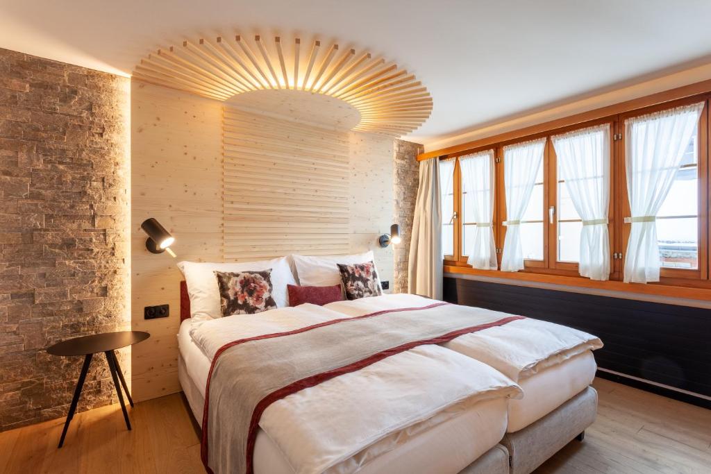 a bedroom with a large bed and a brick wall at Sonne Andermatt Swiss Quality Hotel in Andermatt