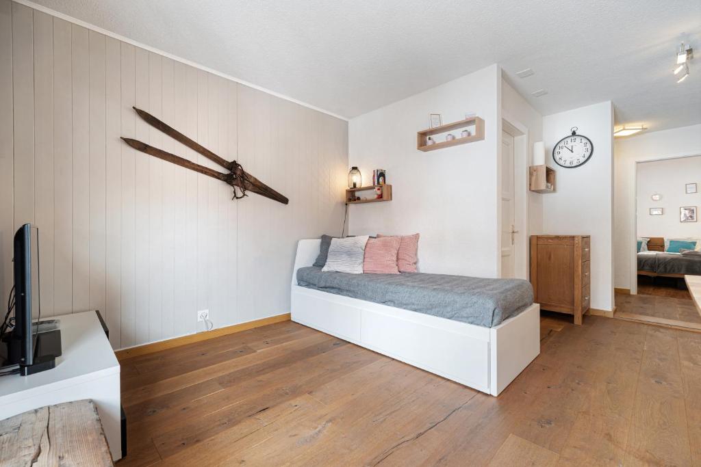 1 dormitorio con 1 cama y reloj en la pared en Appartement chaleureux à Ovronnaz en Ovronnaz